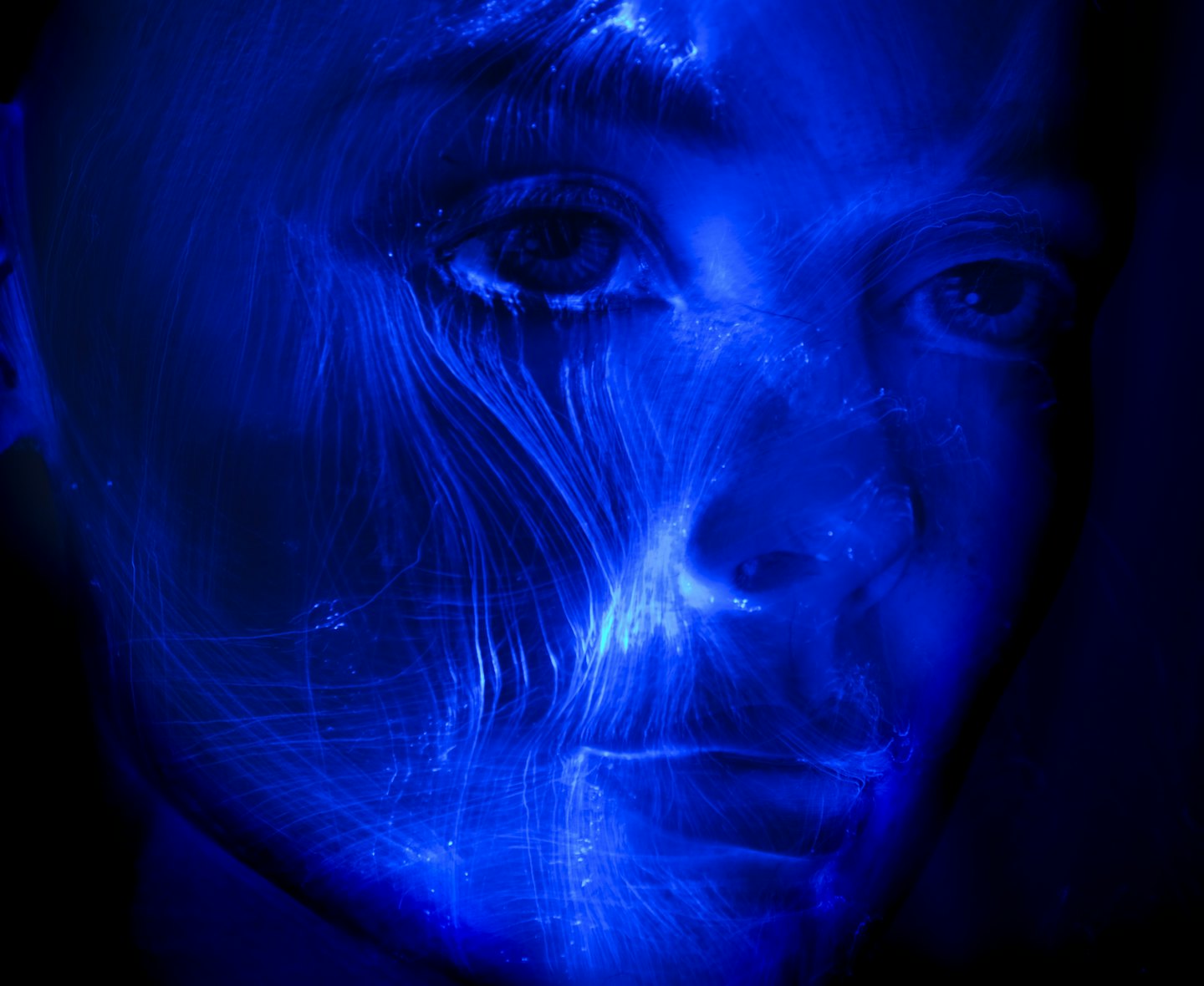 Person's face illuminated by abstract blue light patterns.