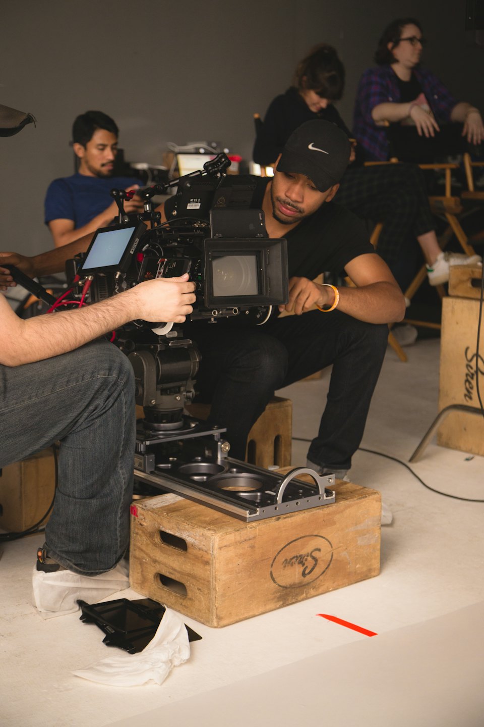 Filmmaker adjusts professional video camera on studio set.